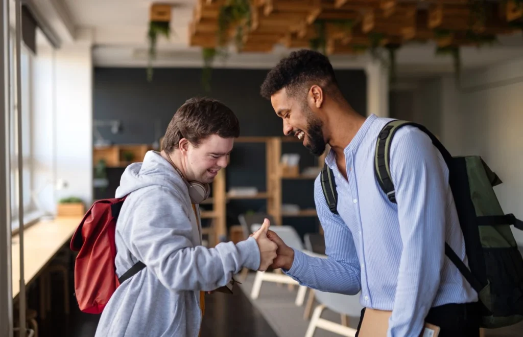 Disabled man with down syndrome shaking hands with support worker both happy
